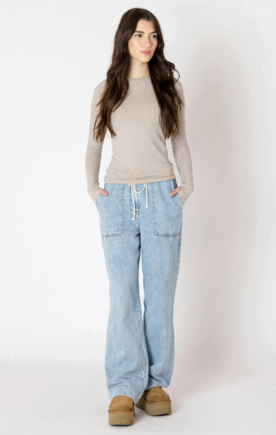 Woman wearing a beige sweater and light blue jeans on a white background