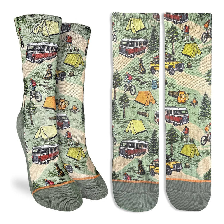 Three pairs of crew socks with a vintage camping print featuring vans, tents, trees, and campfires on a light green background, displayed against a white studio background.