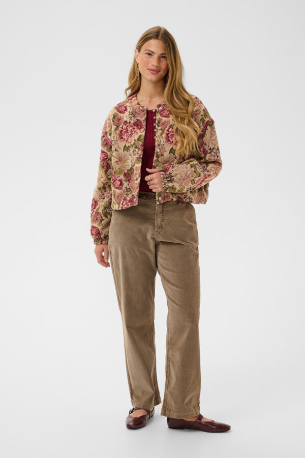 Woman wearing a floral jacket and beige pants on a white background