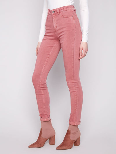 Person wearing pink jeans and matching boots on a white background