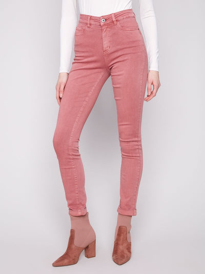 Person wearing pink jeans and brown boots on a white background