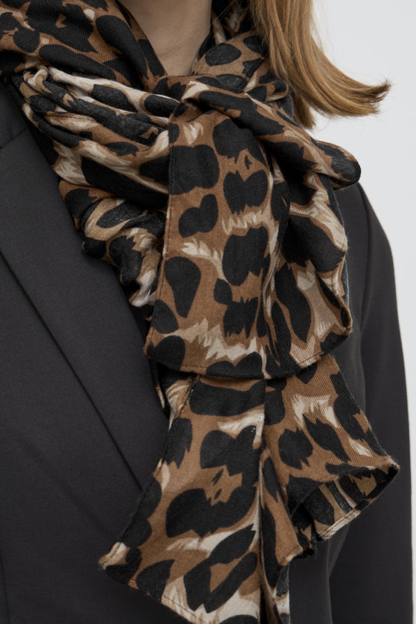 Leopard print scarf draped around a person wearing a black blazer on a white background