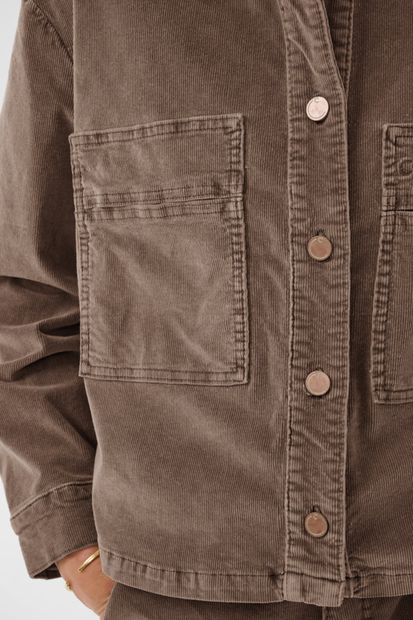 Close-up of a brown corduroy jacket with buttons and a pocket.