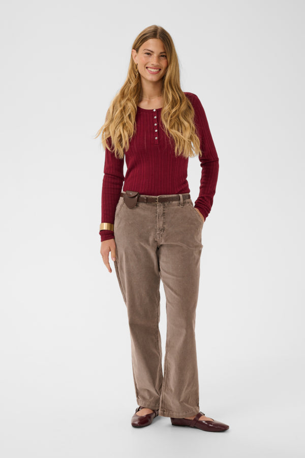 Woman wearing a red sweater and brown pants on a white background
