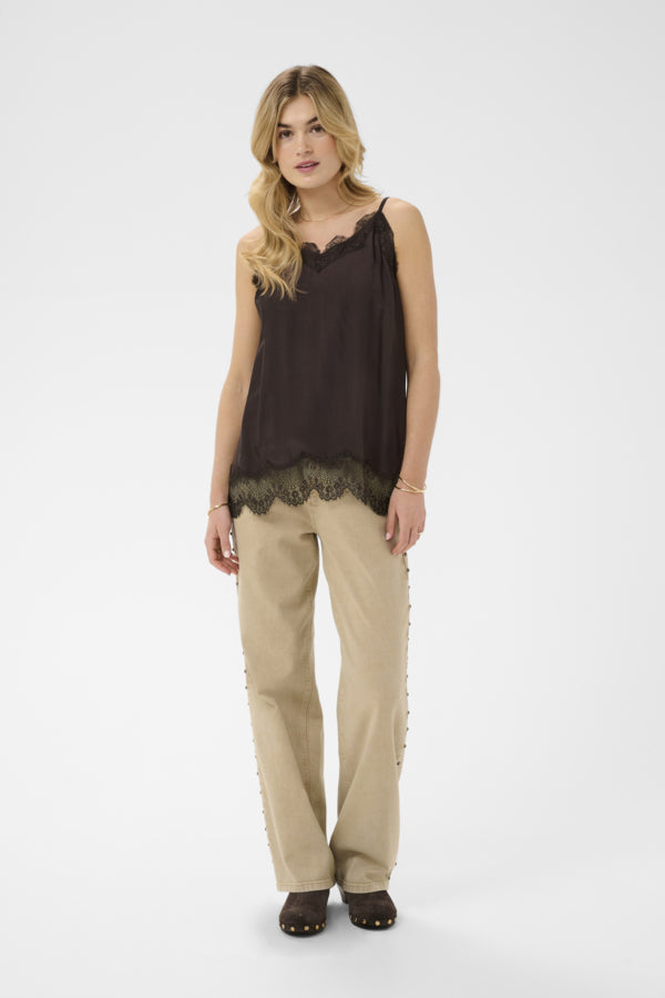 Woman wearing a black sleeveless top and beige pants on a white background