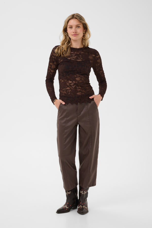 Woman wearing a brown lace top and pants on a white background