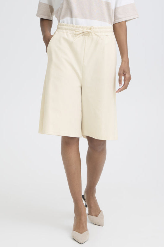 Person wearing light-colored shorts on a white background
