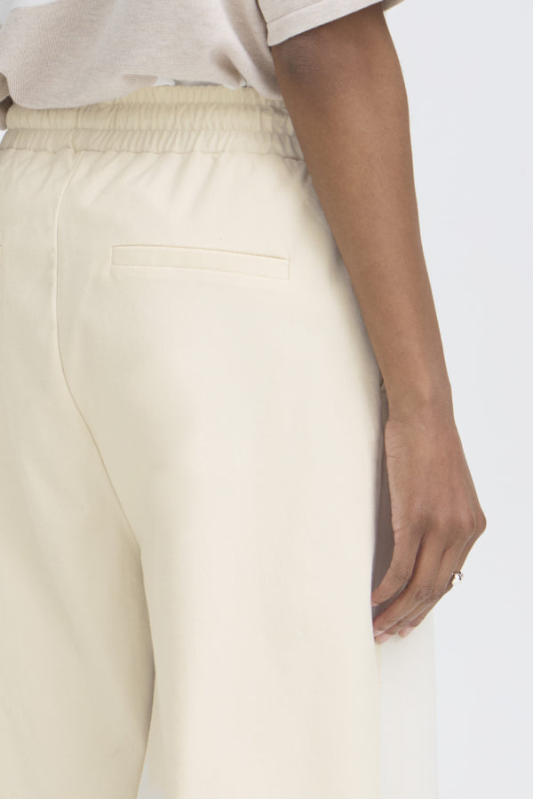 Close-up of a person wearing beige pants on a white background