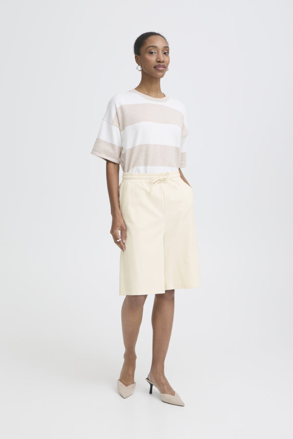 Woman wearing a white and beige striped top with a cream skirt on a white background