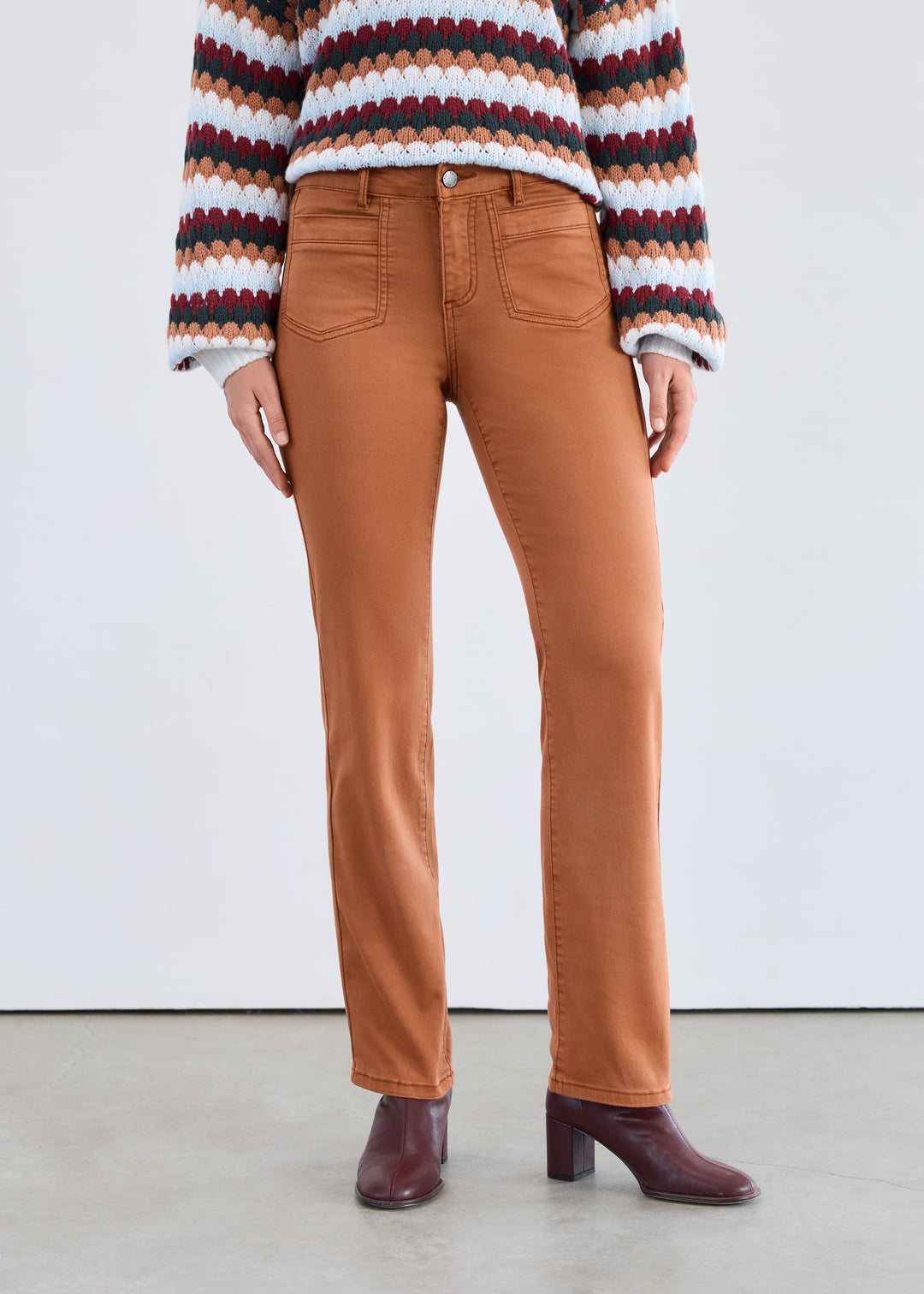 Person wearing a striped sweater, brown pants, and burgundy shoes on a white background