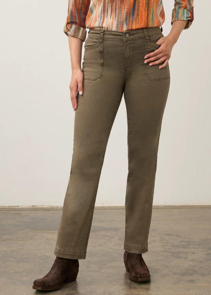 A model wearing olive green straight-leg jeans, a multicolor orange and brown striped long-sleeve shirt, and dark brown leather boots, standing against a neutral studio backdrop.