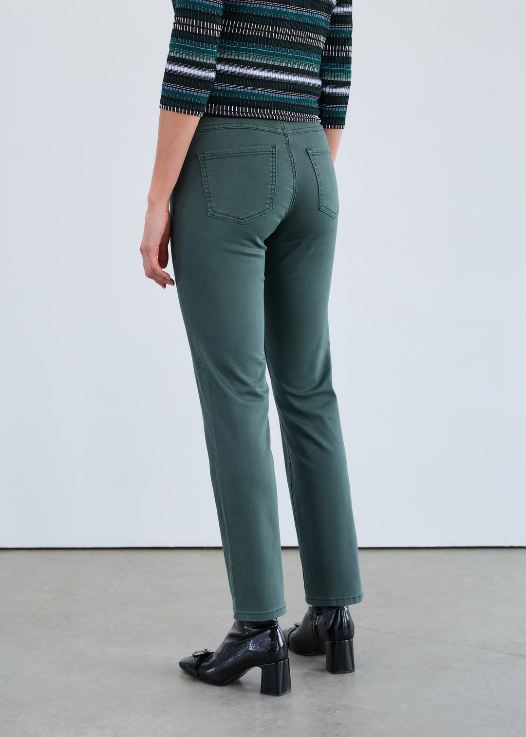 Person wearing green pants and a striped sweater on a plain background