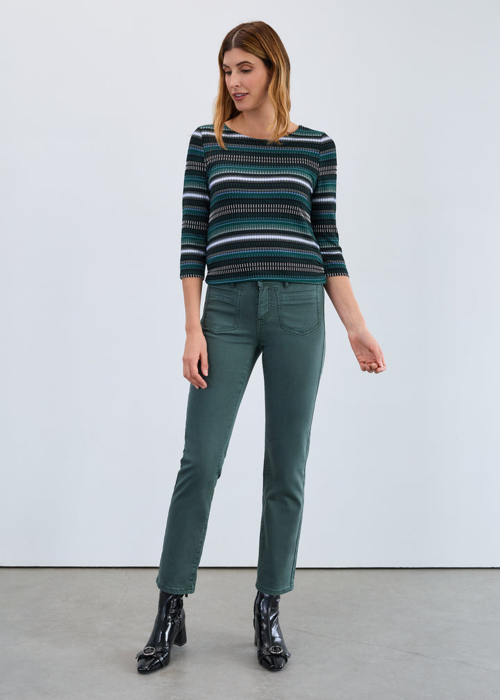 Woman wearing a striped sweater and green pants against a white background