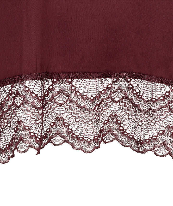 A close-up of a burgundy fabric with a wide, intricate lace hem, shown against a plain white background.
