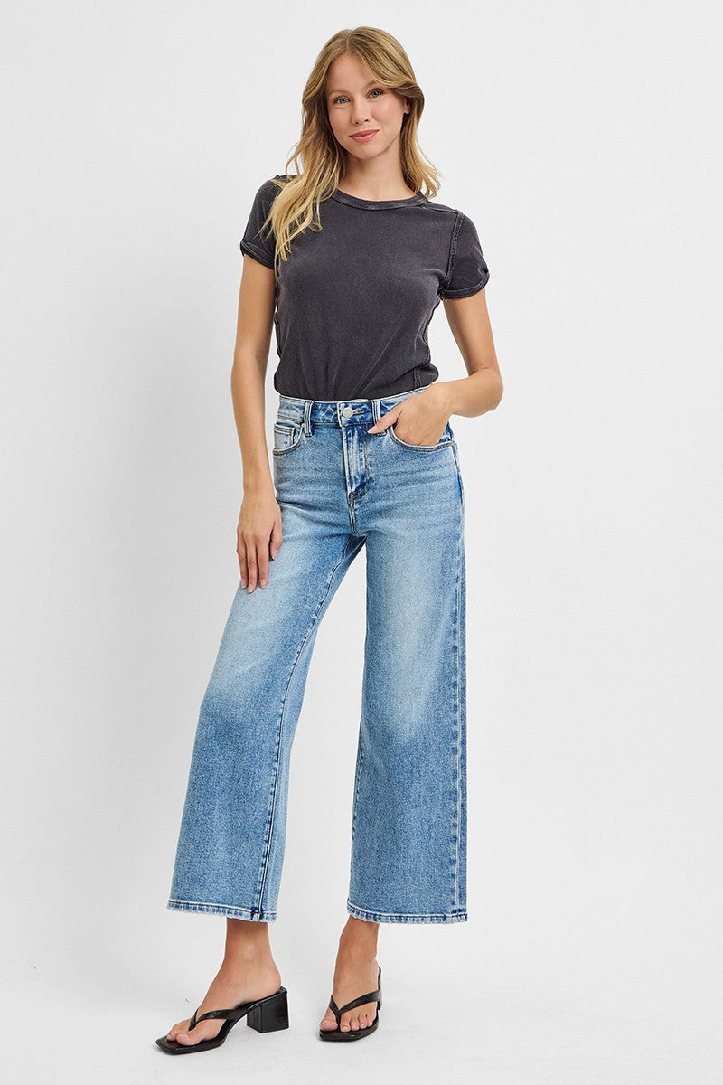 Woman wearing a dark gray t-shirt and light blue jeans on a white background