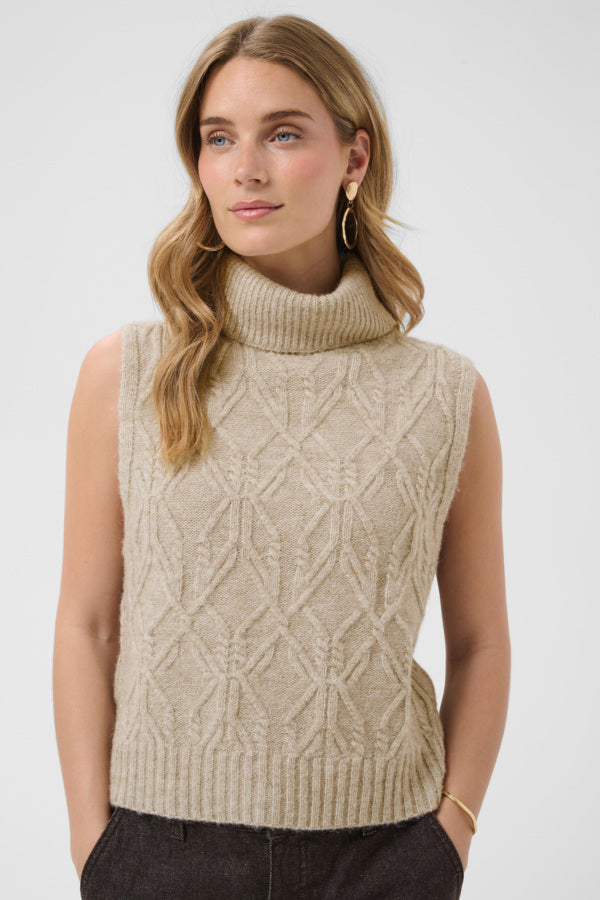 Woman wearing a beige knitted sleeveless sweater against a white background