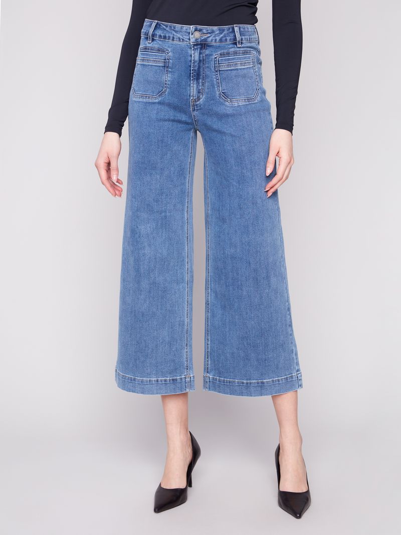 Person wearing blue denim wide-leg jeans on a white background