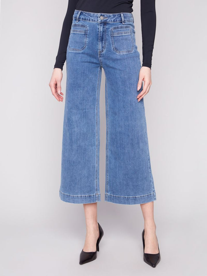 Person wearing blue denim wide-leg jeans on a white background