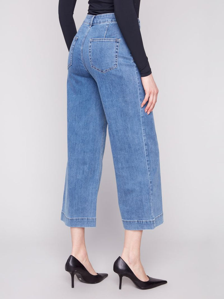 Person wearing blue jeans and black high heels on a plain background