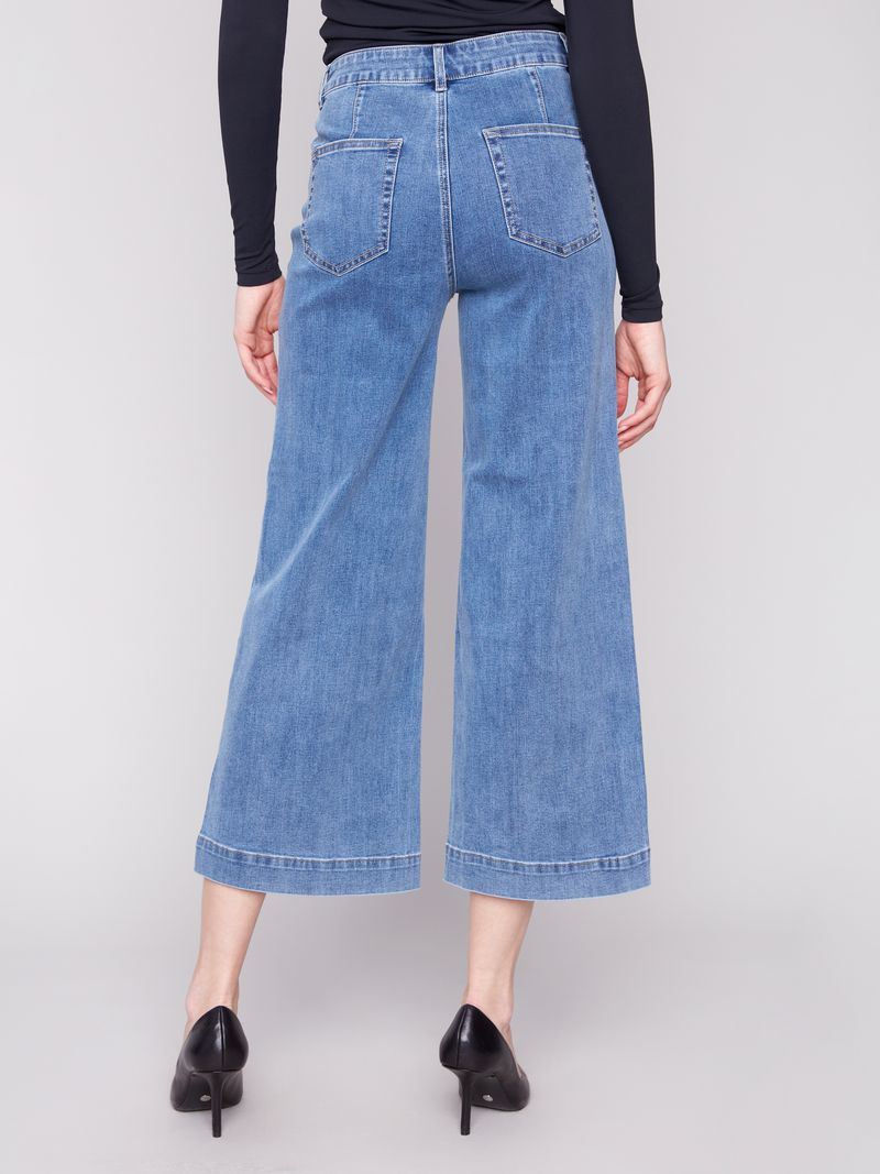 Person wearing blue wide-leg jeans on a plain background
