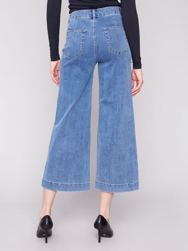 Person wearing blue wide-leg jeans on a plain background