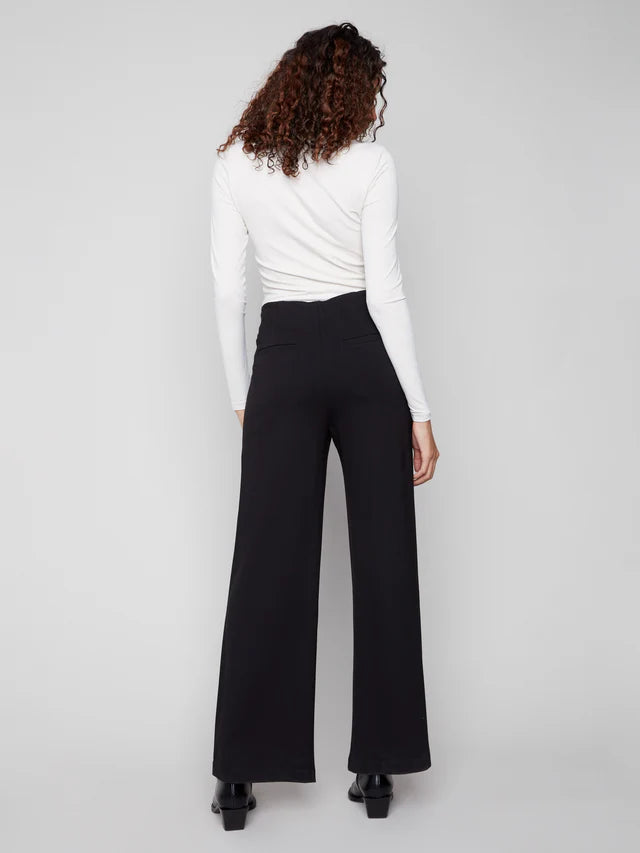 Person wearing a white top and black high-waisted pants on a light gray background