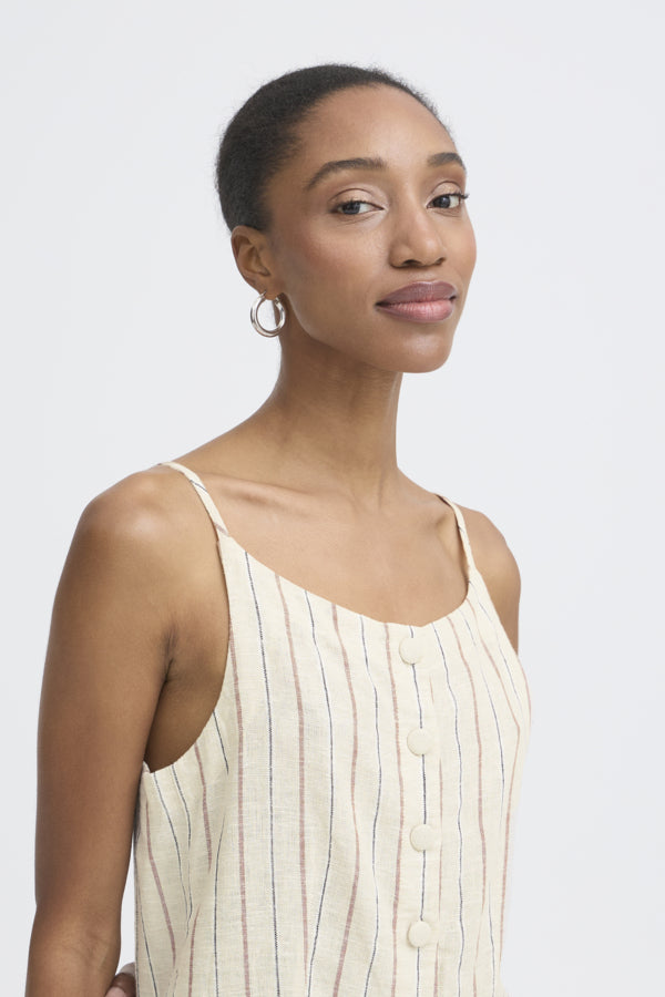 Woman wearing a beige sleeveless top against a plain background