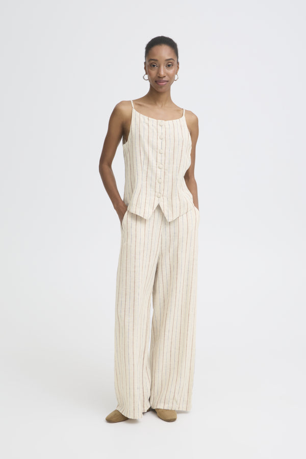 Woman wearing a white sleeveless top and wide-leg pants on a white background