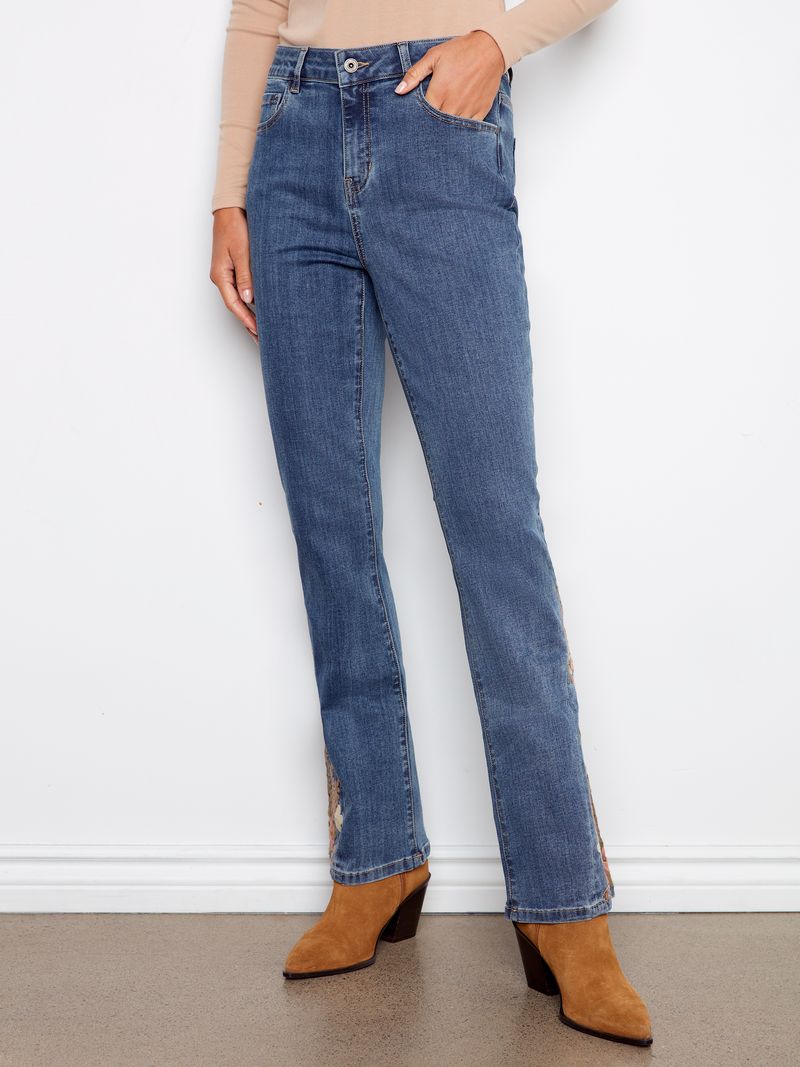 Person wearing blue jeans and brown boots against a white wall