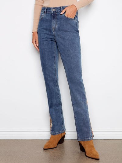 Person wearing blue jeans and brown boots against a white wall