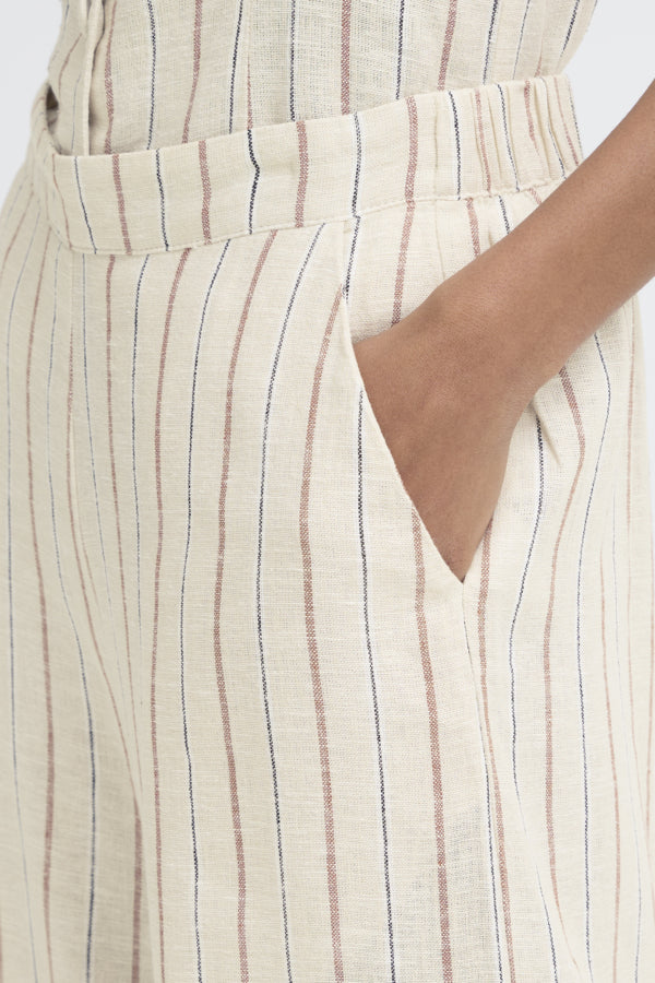 Close-up of a person wearing a beige and brown striped dress with a belt.