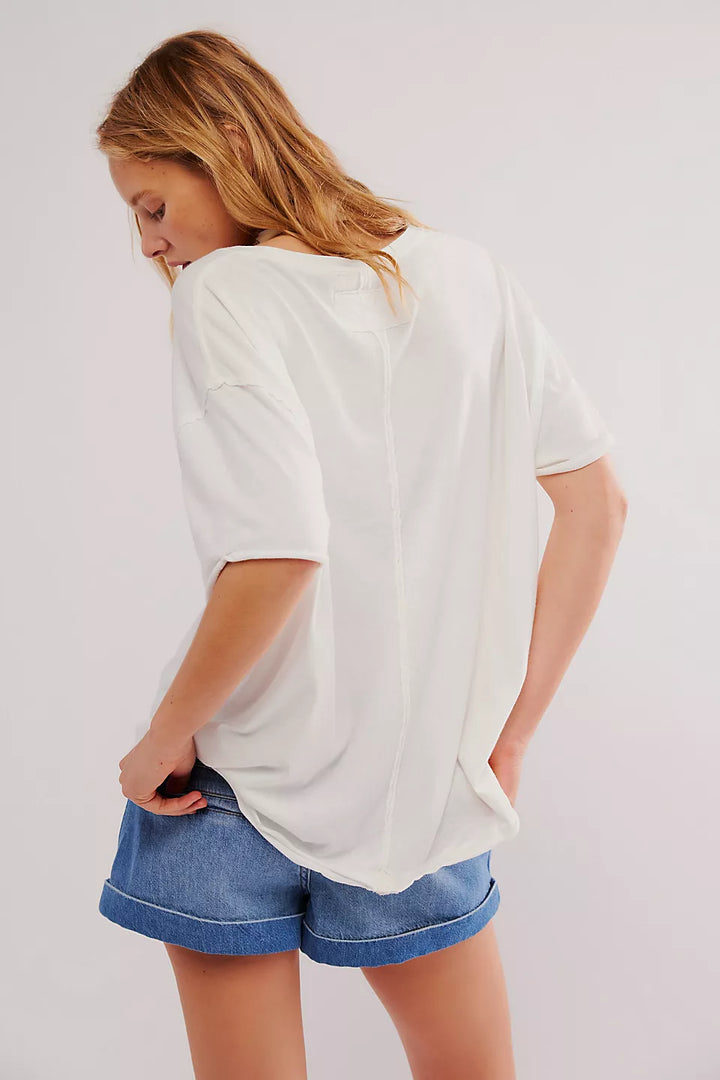 Person wearing a white oversized t-shirt and blue shorts on a plain background
