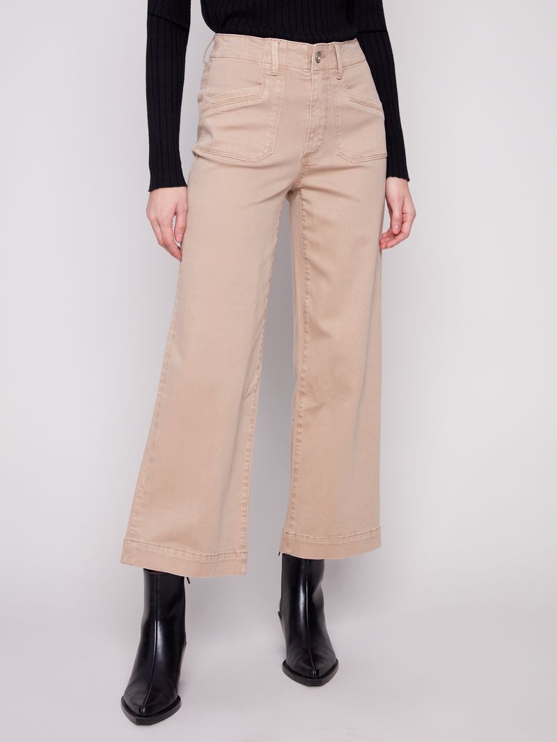 Person wearing beige wide-leg pants and black boots on a white background