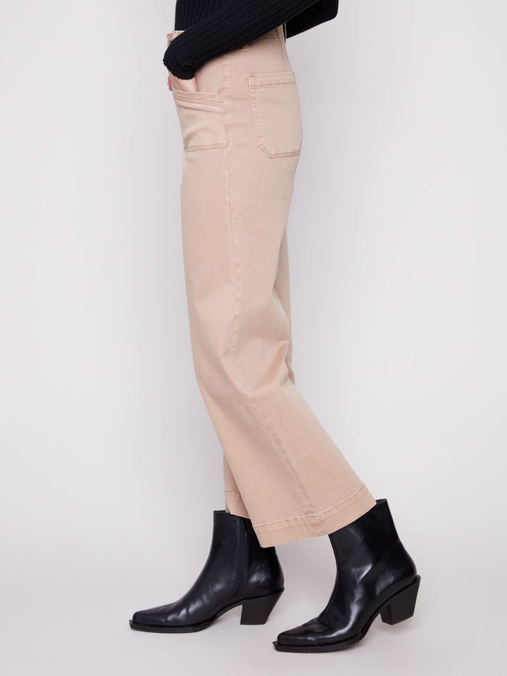 Person wearing beige pants and black ankle boots on a white background