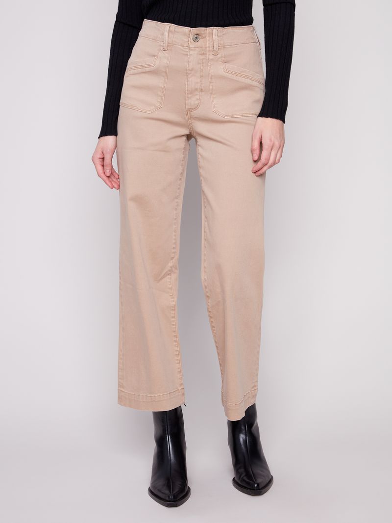 Person wearing beige pants and black boots on a white background
