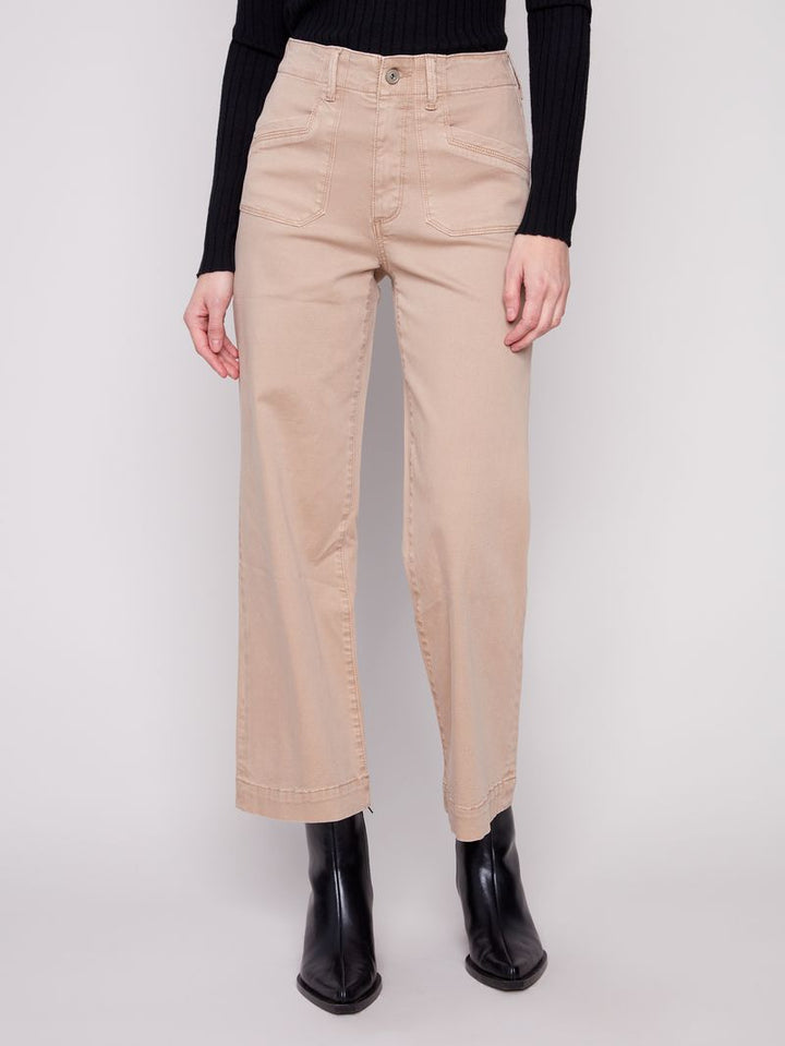 Person wearing beige pants and black boots on a white background