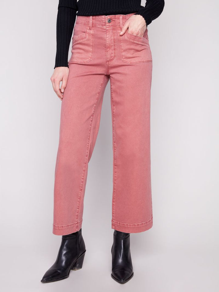 Person wearing pink jeans and black boots on a white background
