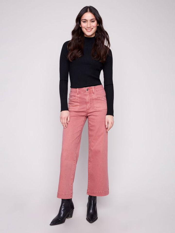 Woman wearing pink jeans and a black top on a white background