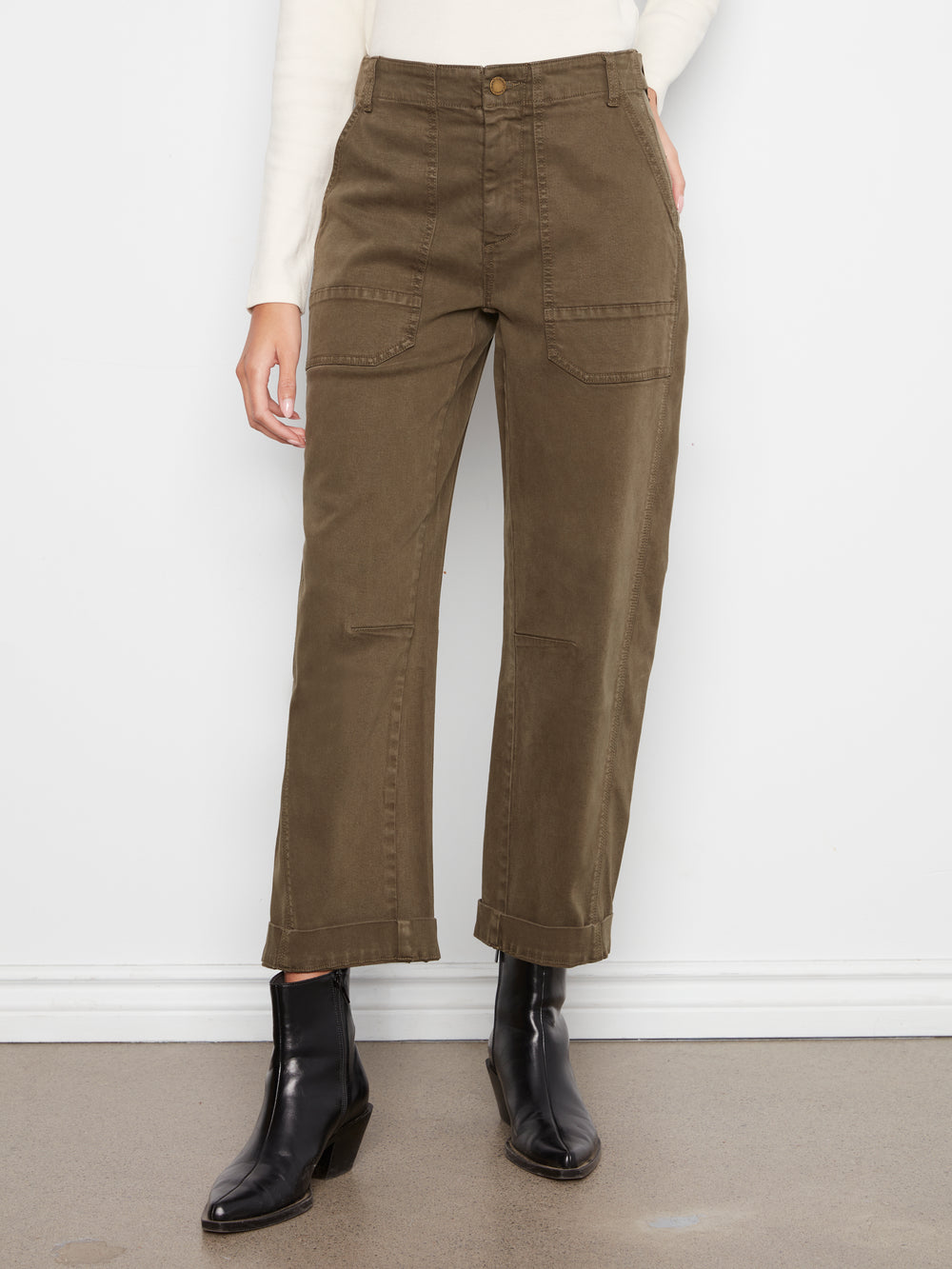 Person wearing olive green pants and black boots against a white background