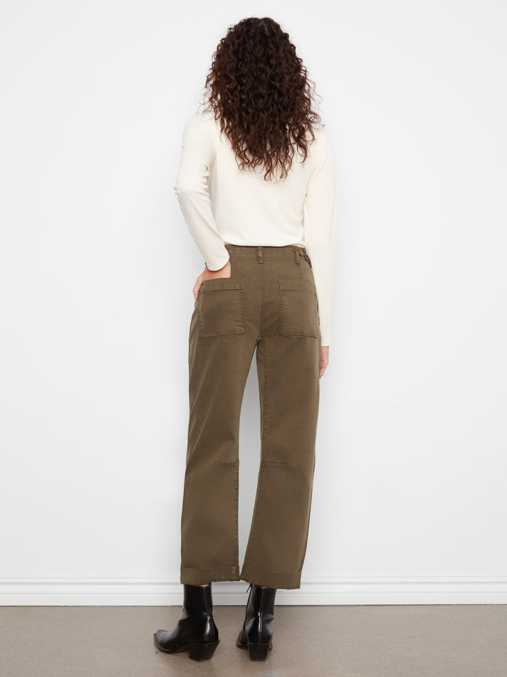 Person wearing olive green pants and a white sweater against a white background