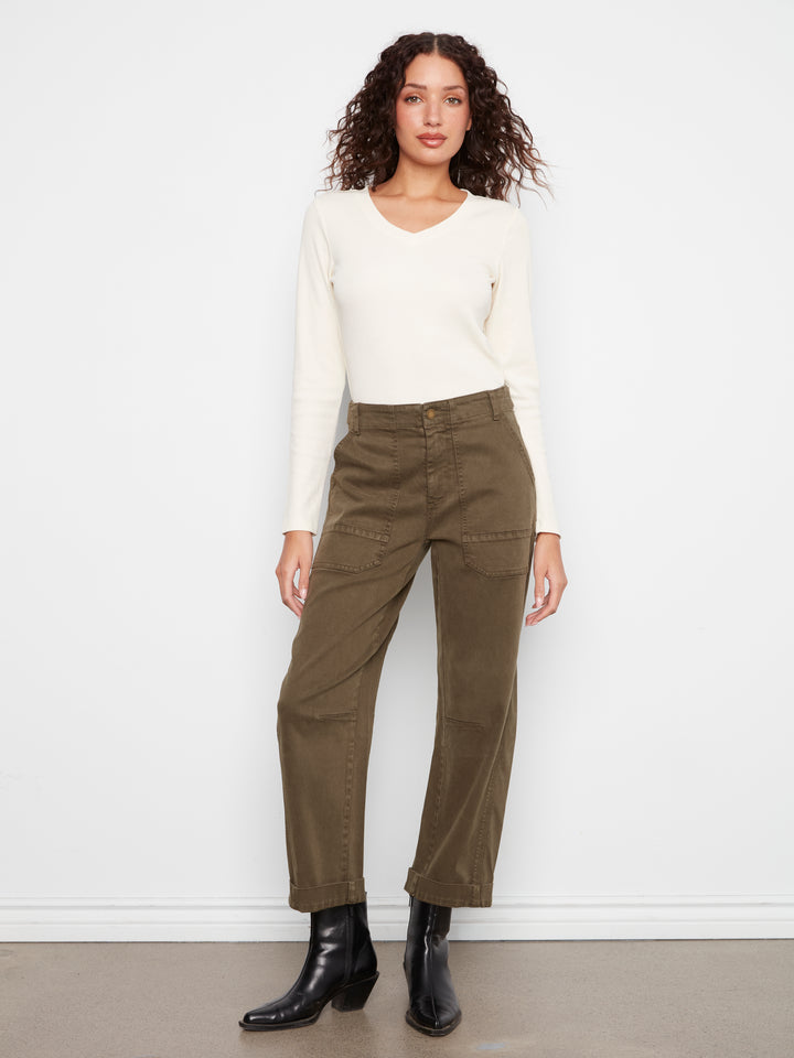 Woman wearing a white top and olive green pants against a white background