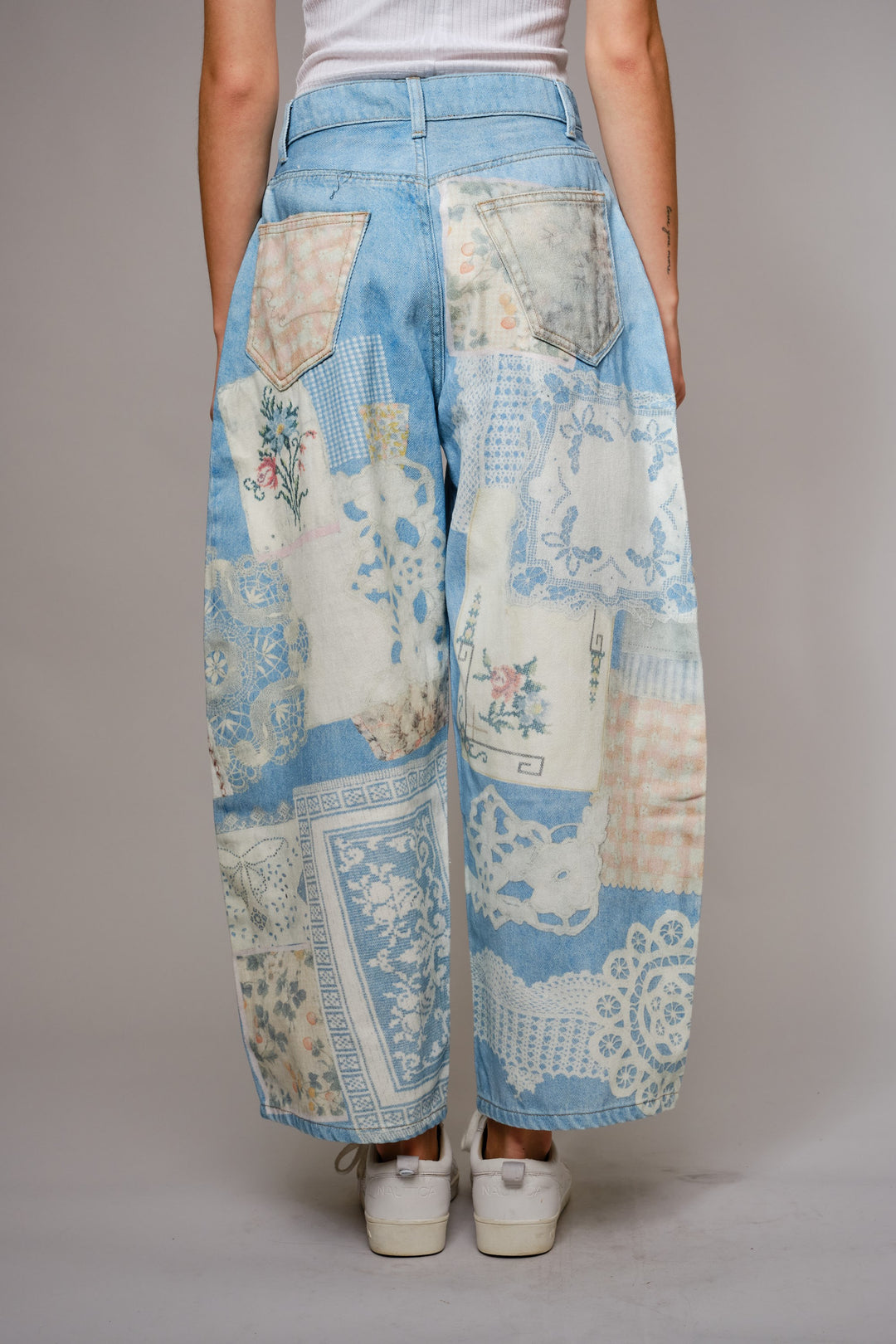 Person wearing patchwork pants with a floral pattern on a plain background