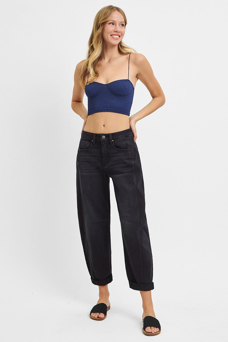 Woman wearing a blue crop top and black jeans on a white background