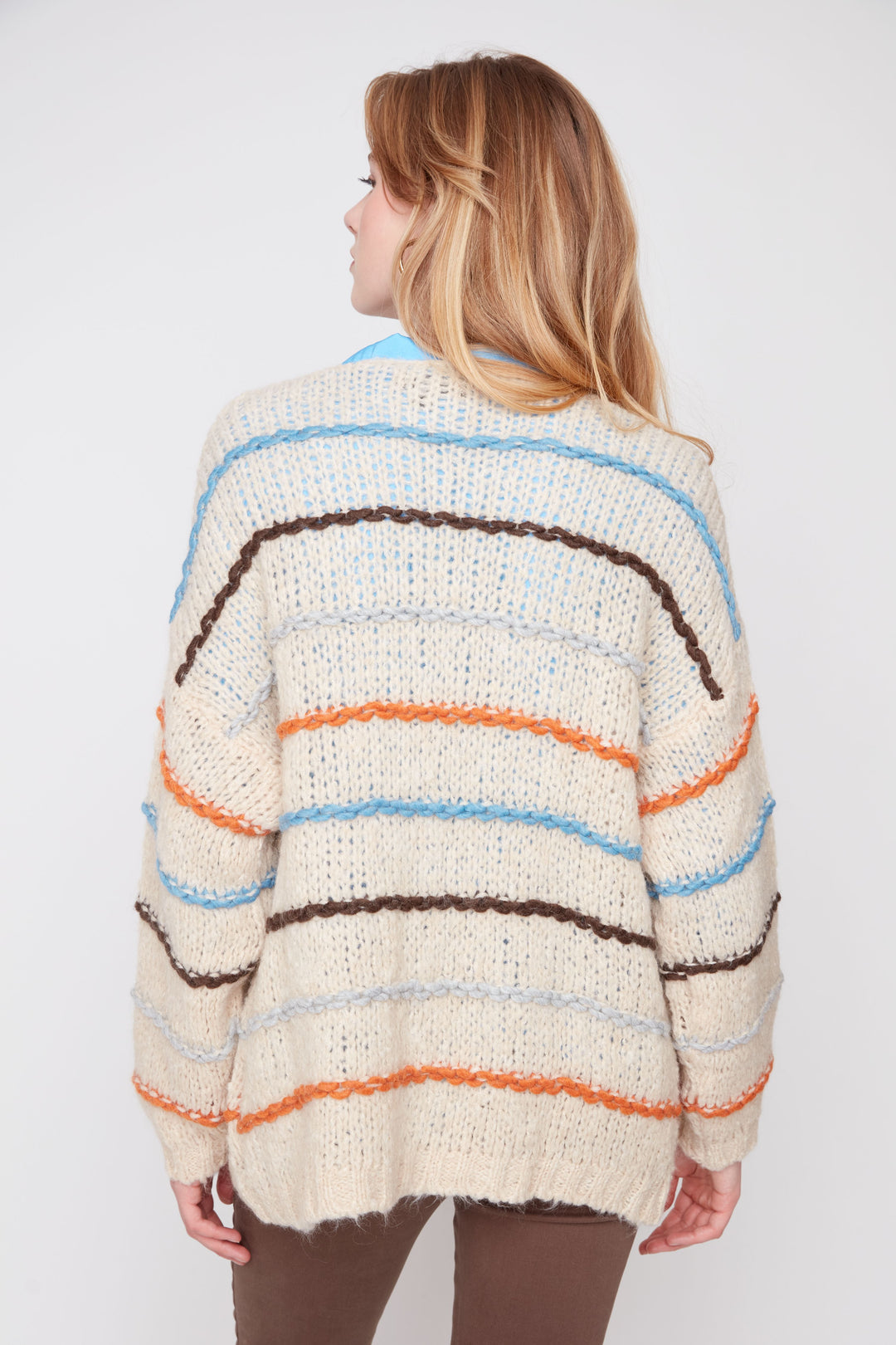 Woman wearing a colorful striped sweater against a white background