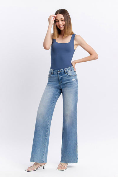 Woman wearing a blue tank top and light blue jeans on a white background