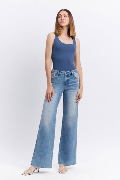 Woman wearing a blue tank top and light blue jeans on a white background