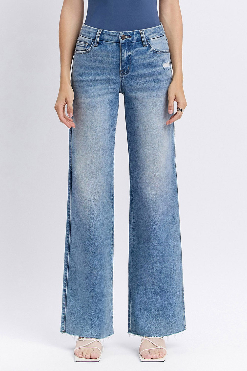 Person wearing light blue flared jeans on a white background