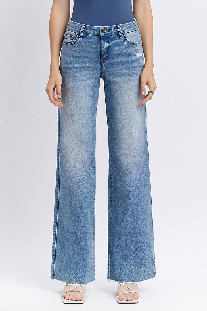 Person wearing light blue flared jeans on a white background