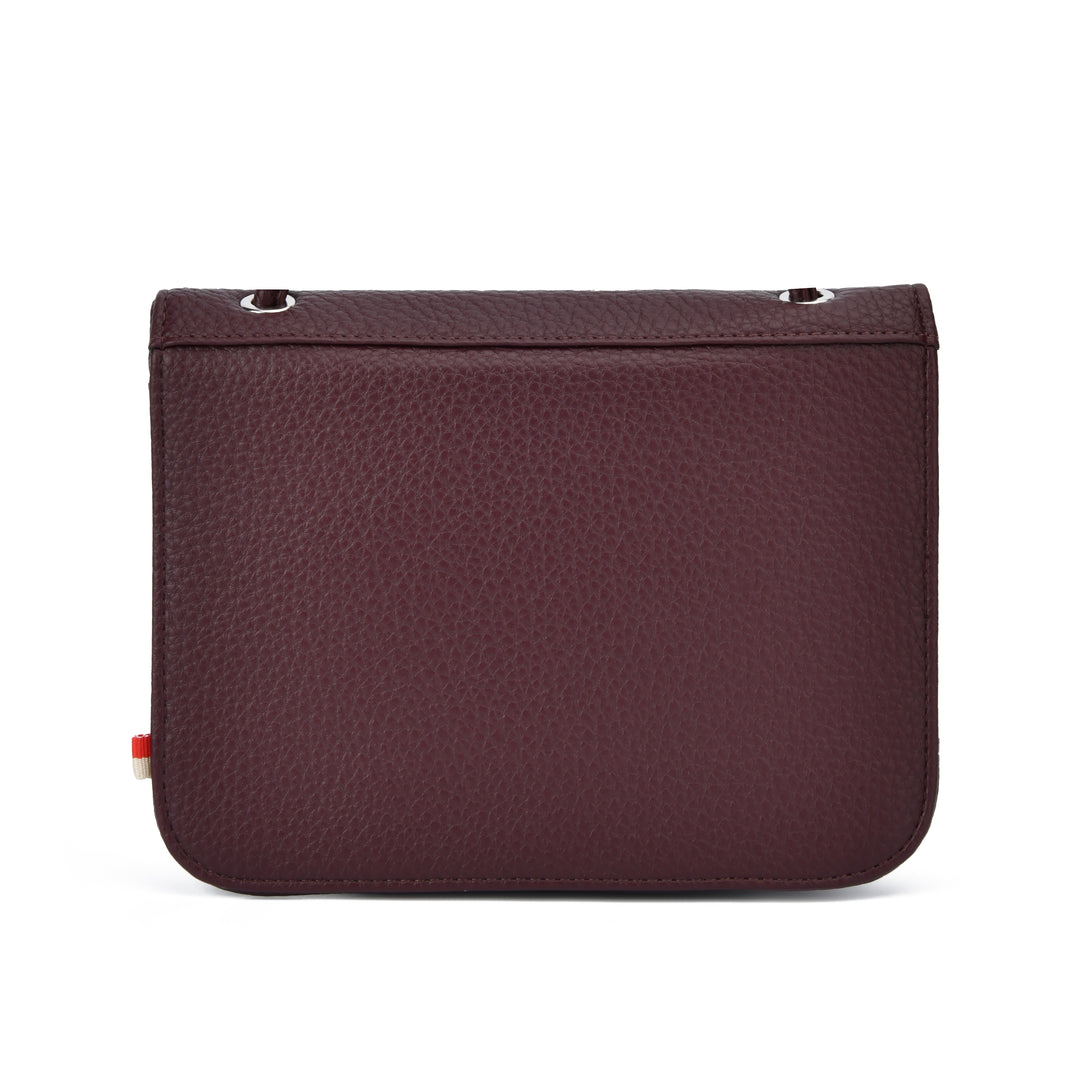 A dark burgundy pebbled leather pouch with a rectangular shape, rounded bottom corners, silver metal grommets on the top edge, and a small red and white tag on the left side, shown against a plain white background.