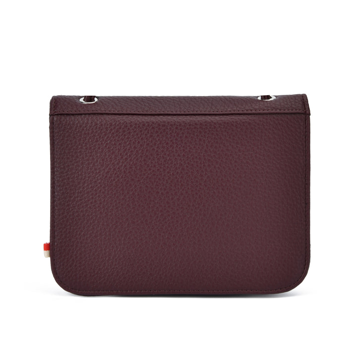 A dark burgundy pebbled leather pouch with a rectangular shape, rounded bottom corners, silver metal grommets on the top edge, and a small red and white tag on the left side, shown against a plain white background.